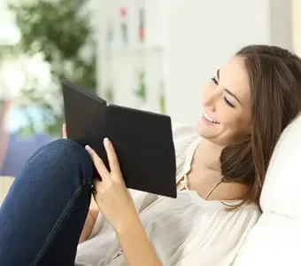 Junge Frau liest mit lachendem Gesicht in einem eBook Reader.