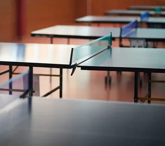 Mehrere Tischtennisplatten stehen in einer Halle