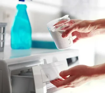 Waschpulver wird mittels einer Dosierhilfe in die Einspülkammer gekippt