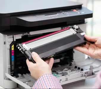 Eine Person setzt eine Tonerkartusche mit Magenta-Farbfüllung in einen Laserdrucker ein