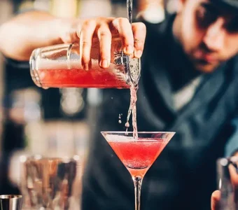 Barkeeper mixt einen Cocktail mit Kirschlikör