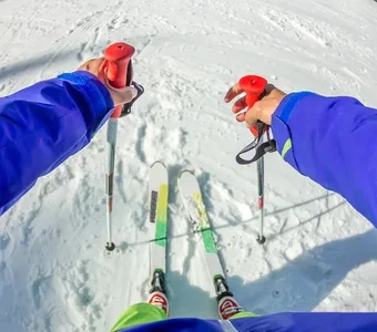 Person steht auf Skiern und mit Stöckern vor einer Abfahrt
