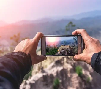 Mann fotografiert eine Landschaft mit einem Smartphone