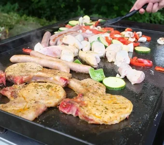 Fleisch und Gemüse wird auf einem Plancha-Grill zubereitet