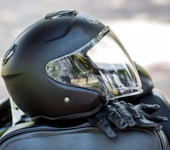 Schwarzer Motorradhelm liegt zusammen mit Lederhandschuhen auf einem Motorradsitz