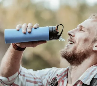 Mann trinkt aus einer blauen Trinkflasche mit Strohhalm
