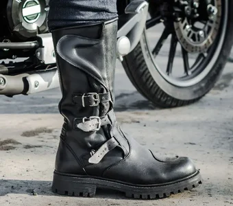 Close-Up von einem Bein mit schwarzem Motorradstiefel  auf Asphalt