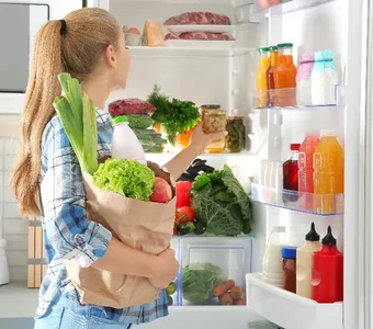 Eine Frau verstaut ihren Einkauf im Kühlschrank