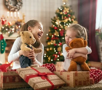 Zwei Mädchen sitzen auf dem Teppich und öffnen Geschenke