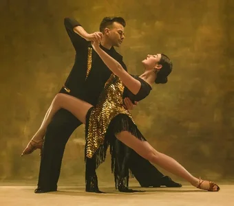 Professionelles Tanzpaar mit einem Outfit in Schwarz und Gold in Tangopose