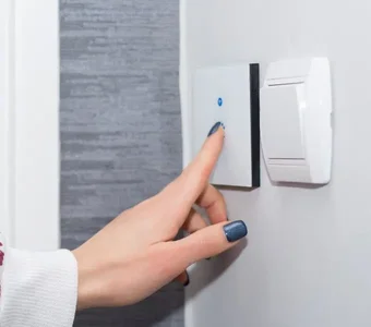 Eine Frau bedient einen Smart Switch Schalter an der Wand