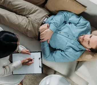 Männliches Model liegt auf der Couch bei einer Psychologin