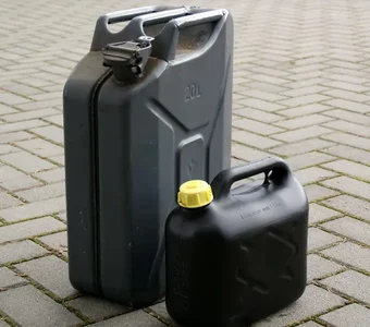 Ein großer grauer Benzinkanister steht neben einem kleinen schwarzen Kanister mit gelbem Deckel