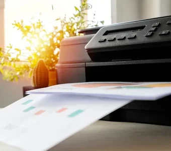 Grauer Tintenstrahldrucker steht auf einem Schreibtisch und druckt