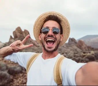 Mann macht Selfie mit dem Smartphone vor einer Landschaft