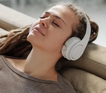Model sitzt auf einem Sofa und trägt Over-Ear-Kopfhörer von Samsung