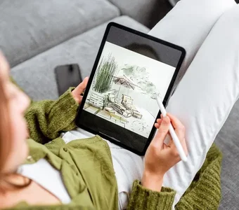 Frau sitzt auf einer Couch und zeichnet mit einem Smart Pen auf einem Android Tablet