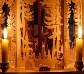 Ausschnitt einer mehrstöckigen Weihnachtspyramide mit Holzfiguren und Kerzen