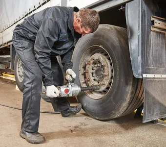 Mechaniker schraubt einen LKW Reifen mit einem Druckluftschrauber fest