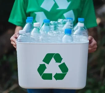 Person hält Mülleimer mit Plastikflaschen für Recycling