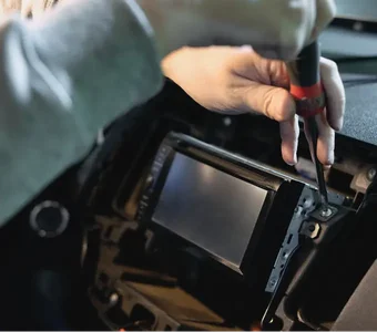 Techniker schraubt an Doppel-DIN-Autoradio mit Bildschirm