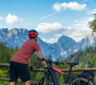 Mann steht neben seinem Elektro Trekkingbike und schaut auf Berge