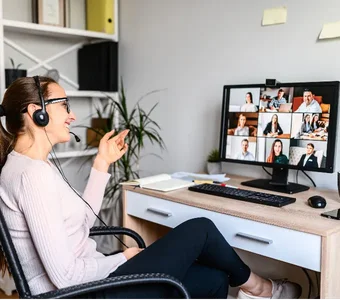 Frau mit Headset sitzt bei einem Video-Call-Meeting