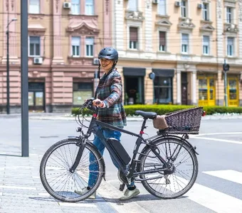 Frau schiebt ihr E-Citybike über einen Zebrastreifen in der Stadt