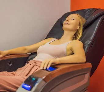 Eine Frau sitzt auf einem schwarzen Massagesessel