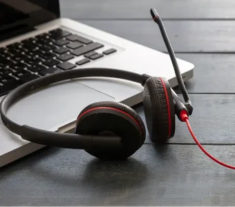 Headset mit Kabel liegt auf Holztisch mit Laptop