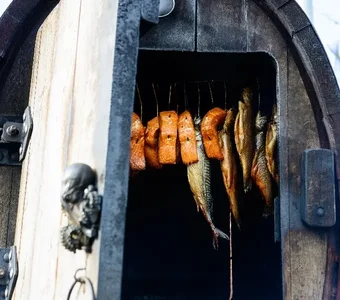 In einem Holzfass-Räücherofen wird Fisch geräuchert