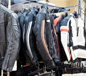 Motorradjacken aus Leder und Textil hängen an Bügeln in einem Bekleidungsgeschäft