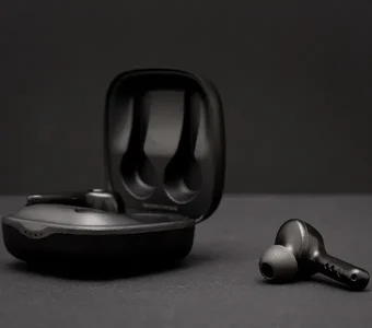Schwarze True Wireless Kopfhörer mit einem Ladecase liegen auf einem grauen Untergrund