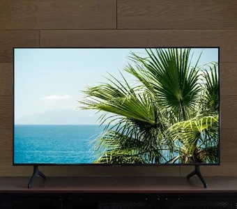OLED Fernseher steht auf einem Lowboard vor brauner Wand