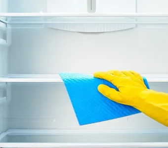 Leerer Kühlschrank wird mit einem Mikrofasertuch von Schmutz befreit
