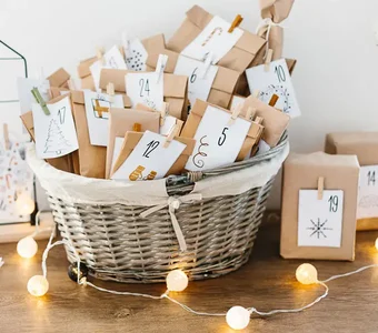 Nummerierte, weihnachtlich dekorierte Papiertütchen in einem Korb mit Lichterkette
