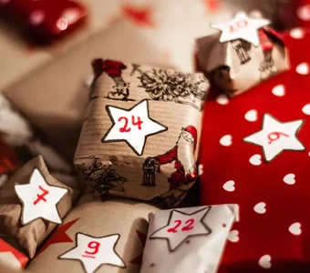 In weihnachtliches Papier eingeschlagene Päckchen mit Zahlenaufklebern liegen nebeneinander
