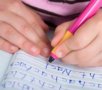 Kind, das Schreibübungen in einem Schreiblernheft macht