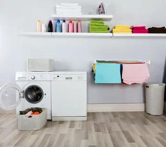 Waschmaschine, Trockner, Bügelbrett und -eisen sowie Wäschekörbe und frisch gewaschene Wäsche in einem Raum