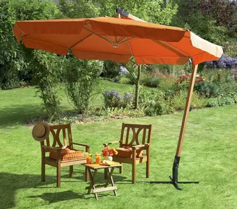 Oranger Ampelsonnenschirm auf einer Wiese mit Stühlen darunter