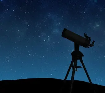 Abbildung eines Teleskopes auf einem Stativ bei Nacht.