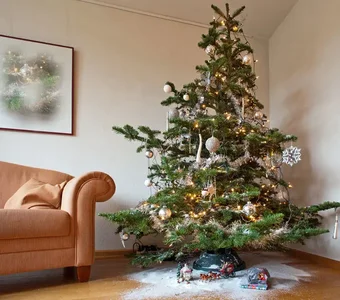 Ein geschmückter Weihnachtsbaum steht auf einem mit Kunstschnee bedecktem Holzboden