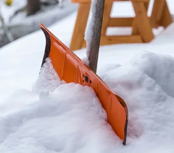 Detailaufnahme einer Schaufel, die im Schnee steckt