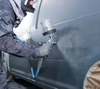 Ein Van wird mit Hilfe einer Sprühpistole schwarz lackiert