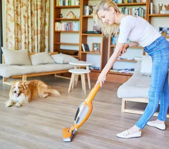 Frau saugt ihr Wohnzimmer mit einem Staubsauger