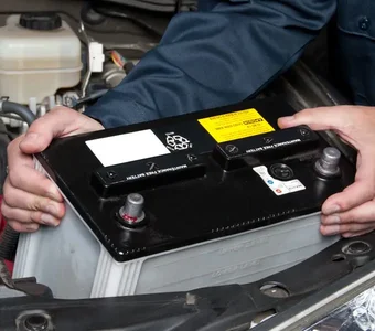 Eine Autobatterie wird vom Fachpersonal aus dem Motorraum entnommen