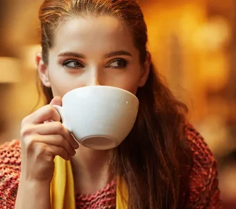 Eine junge Frau trinkt ihren Kaffee aus einer weißen Tasse