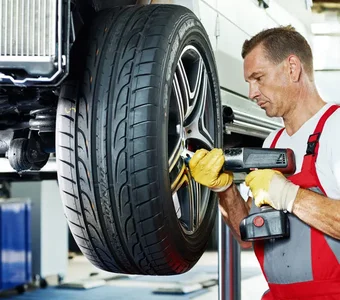Kfz-Mechaniker wechselt die Reifen an einem Wagen