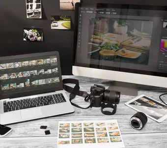 Schreibtisch mit PC, Laptop, Kamera und Bildern