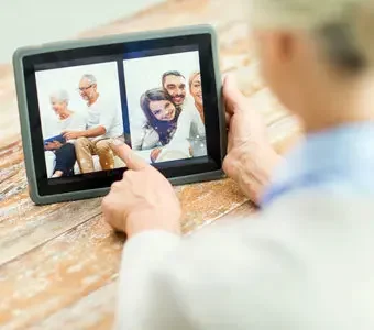 Eine ältere Frau scrollt mit einem digitalen Bilderrahmen durch Familienfotos